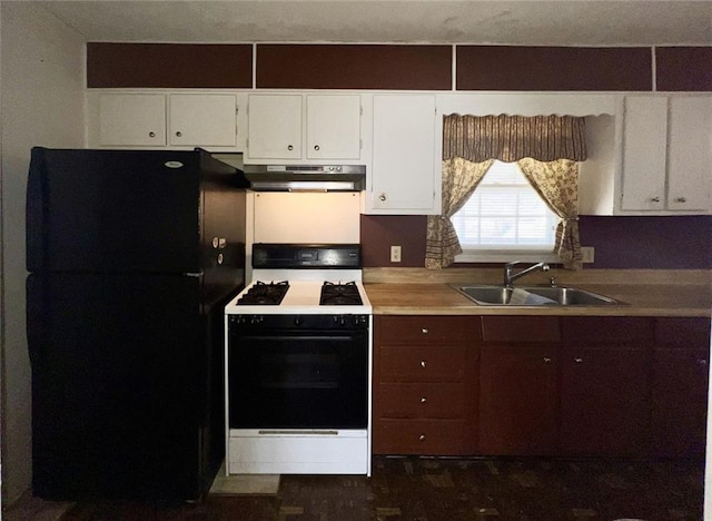 kitchen with under cabinet range hood, a sink, white cabinetry, gas stove, and freestanding refrigerator