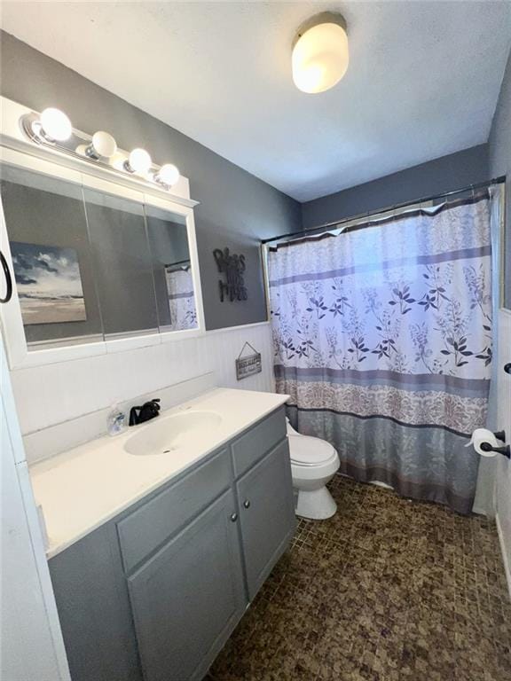 bathroom featuring curtained shower, vanity, wainscoting, and toilet