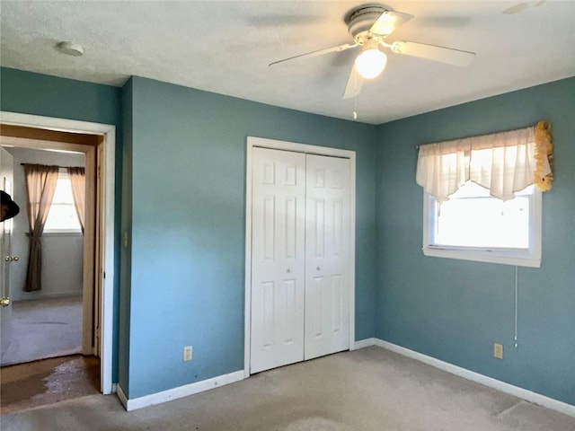 unfurnished bedroom featuring baseboards, multiple windows, carpet, and a closet