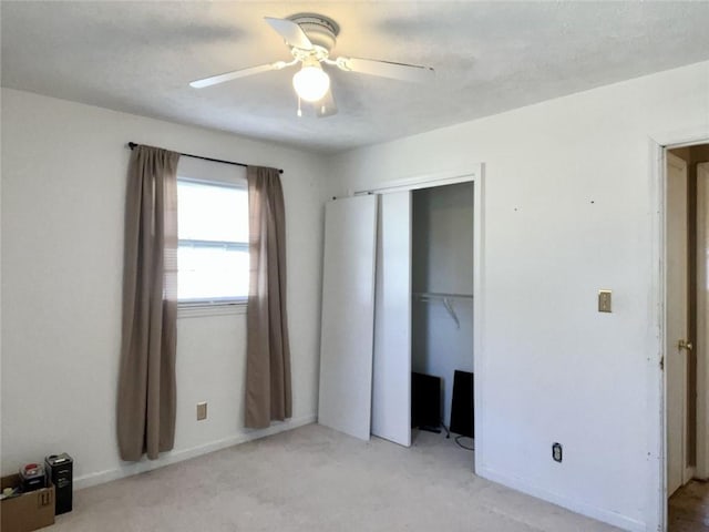 unfurnished bedroom with ceiling fan, a closet, and light carpet