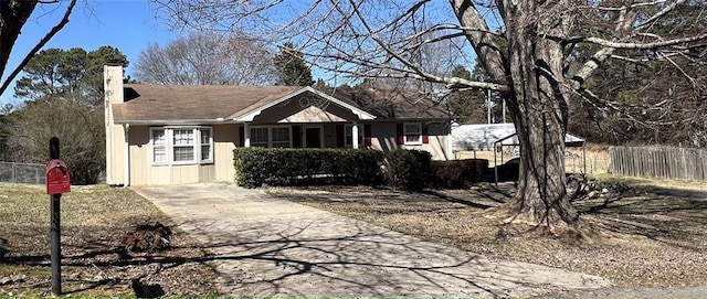 view of front of property featuring driveway, a chimney, and fence