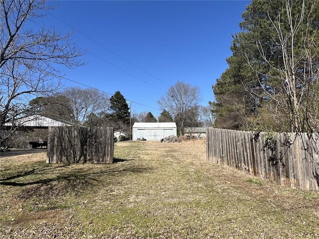 view of yard featuring an outdoor structure, a shed, and fence