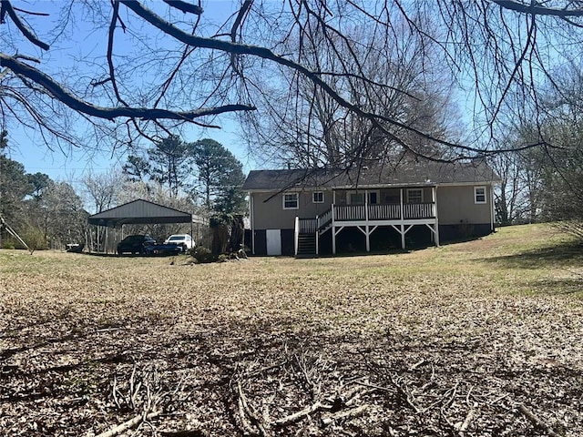 back of house with stairs, a carport, and a yard