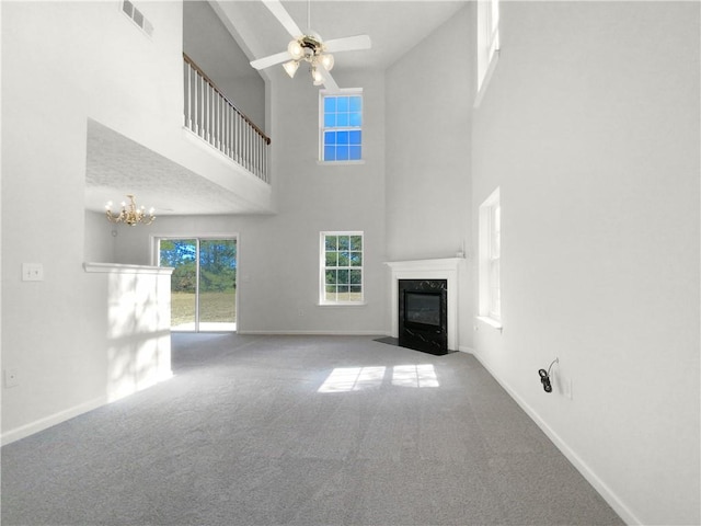 unfurnished living room featuring a towering ceiling, carpet floors, ceiling fan, and a high end fireplace