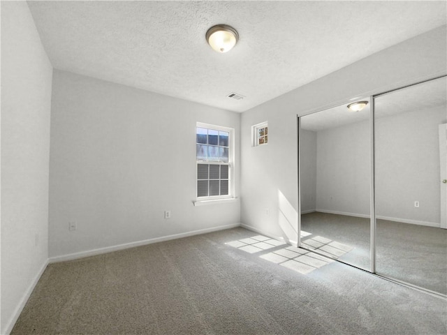 unfurnished room with a textured ceiling, carpet floors, and ceiling fan