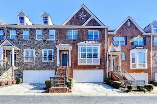 multi unit property featuring a garage, stairs, concrete driveway, and brick siding