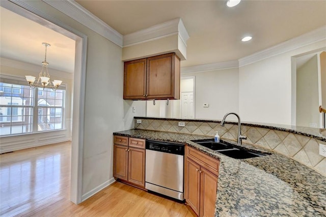 kitchen with light wood finished floors, dishwasher, brown cabinets, dark stone countertops, and a sink