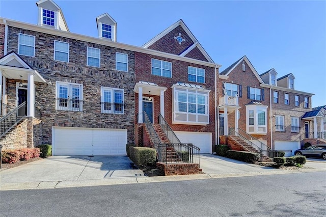 multi unit property with concrete driveway, brick siding, stairway, and an attached garage