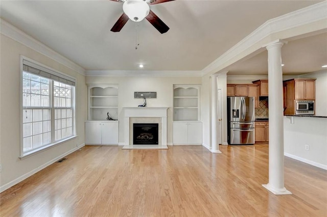 unfurnished living room featuring light wood-style floors, decorative columns, crown molding, and a glass covered fireplace