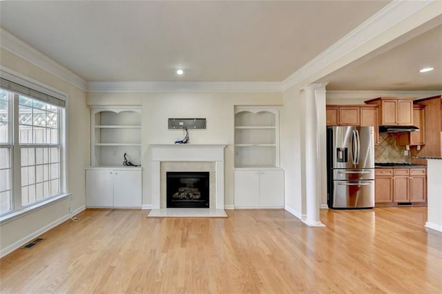 unfurnished living room featuring light wood-type flooring, visible vents, crown molding, and ornate columns