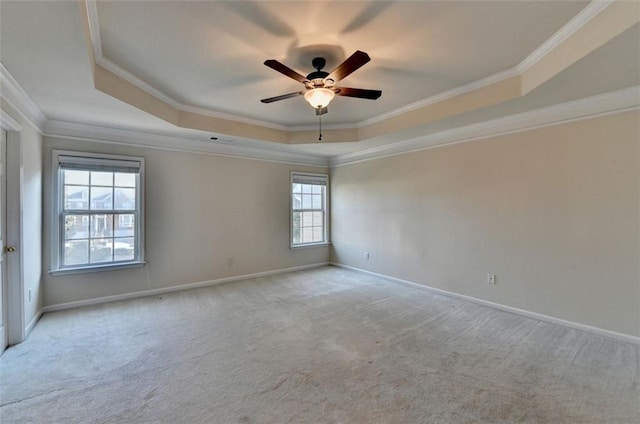 empty room featuring baseboards, a tray ceiling, crown molding, and light colored carpet