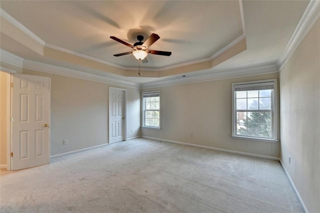 unfurnished room featuring light carpet, a tray ceiling, crown molding, and baseboards