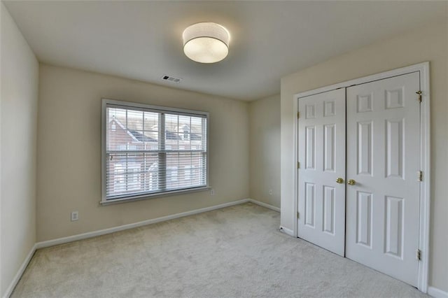 unfurnished bedroom with light carpet, a closet, visible vents, and baseboards