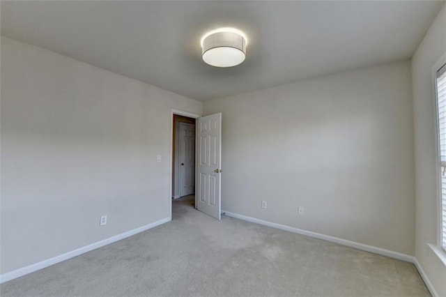 unfurnished room featuring light carpet and baseboards