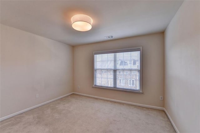 spare room with baseboards, visible vents, and light colored carpet