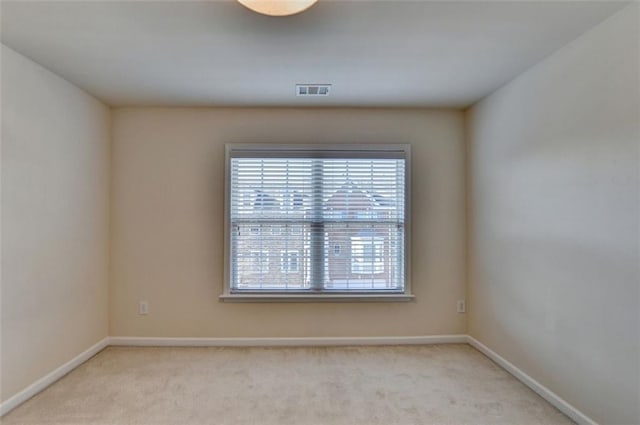 unfurnished room featuring light colored carpet, visible vents, and baseboards