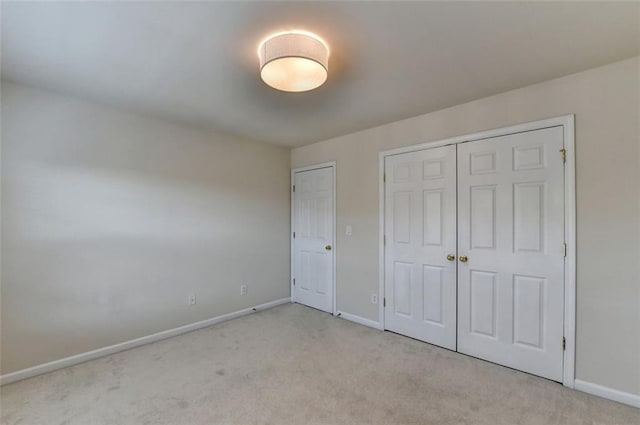 unfurnished bedroom featuring a closet, light colored carpet, and baseboards