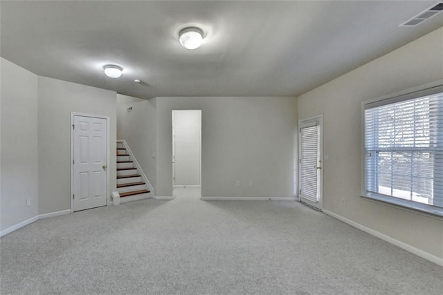 empty room featuring light colored carpet, visible vents, stairway, and baseboards