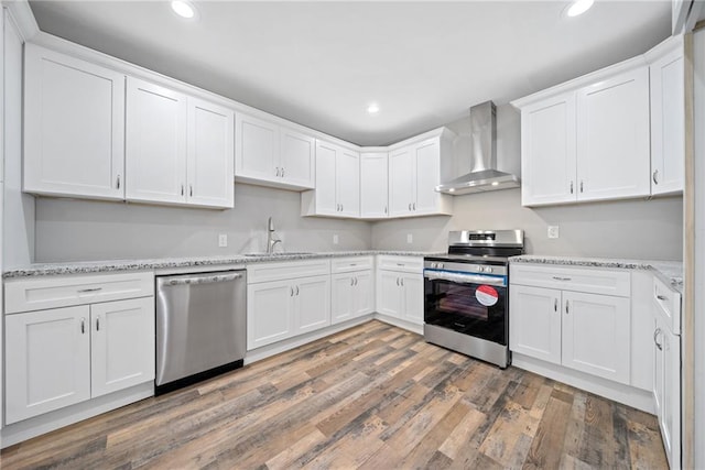 kitchen with white cabinets, stainless steel appliances, sink, and wall chimney exhaust hood