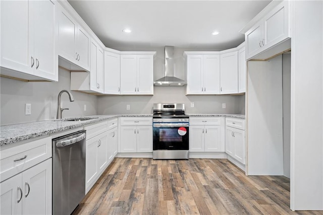 kitchen featuring appliances with stainless steel finishes, sink, white cabinets, and wall chimney exhaust hood