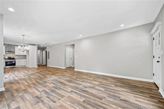 unfurnished living room featuring an inviting chandelier and light hardwood / wood-style floors