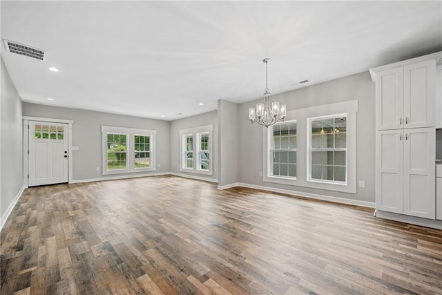 unfurnished living room featuring an inviting chandelier and wood-type flooring