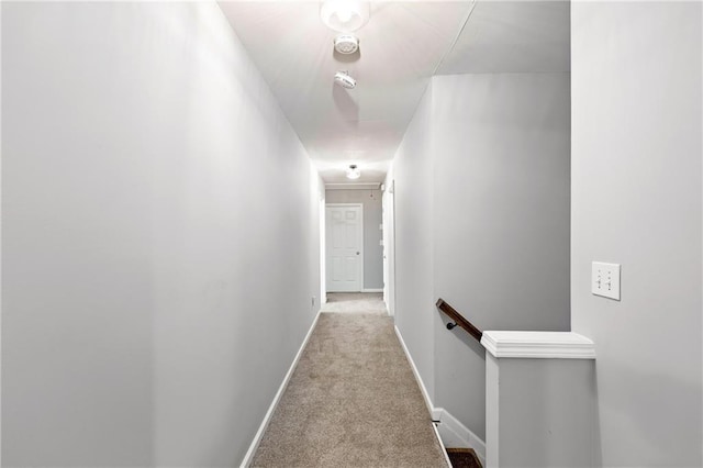 corridor with baseboards, carpet flooring, and an upstairs landing