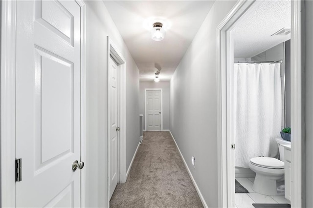 hall featuring visible vents, baseboards, and carpet flooring