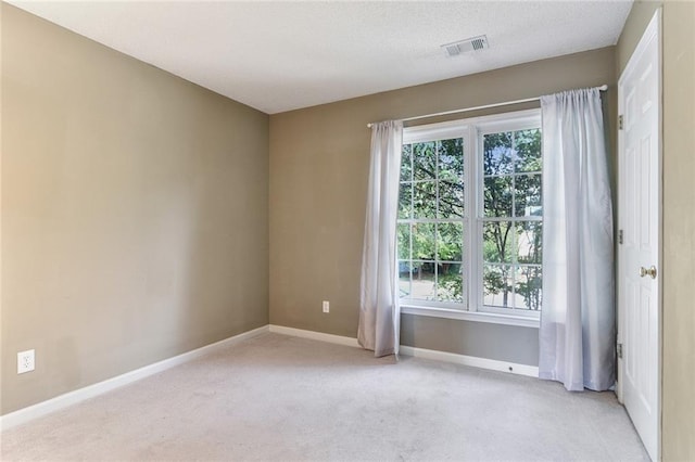 carpeted empty room with a textured ceiling, visible vents, and baseboards