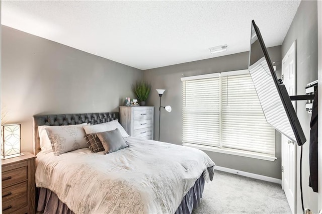 bedroom featuring light colored carpet, visible vents, baseboards, and a textured ceiling