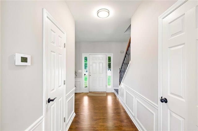 foyer entrance featuring a wainscoted wall, dark wood-style flooring, and a decorative wall