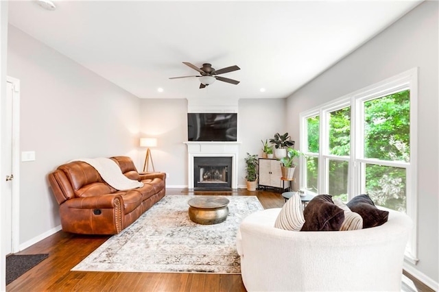 living room featuring recessed lighting, dark wood-type flooring, a fireplace with flush hearth, a ceiling fan, and baseboards