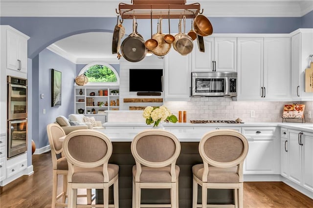 4020 Devereux Chase, Roswell, GA 30075 - kitchen with appliances with stainless steel finishes, arched walkways, ornamental molding, a breakfast bar, and dark wood-type flooring