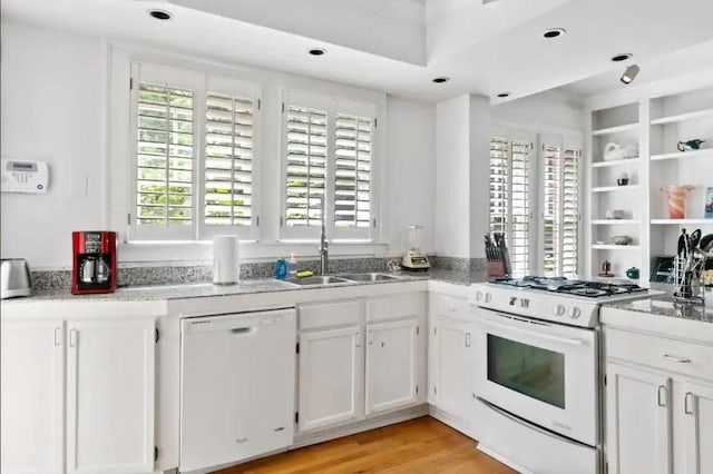 kitchen with light wood-type flooring, white appliances, sink, and white cabinets