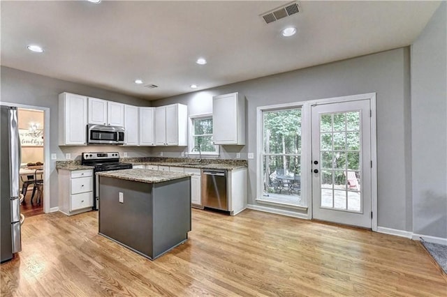 6520 Fairfield Trce, Suwanee, GA 30024 - kitchen featuring stainless steel appliances, white cabinetry, light wood finished floors, a center island, and light stone countertops