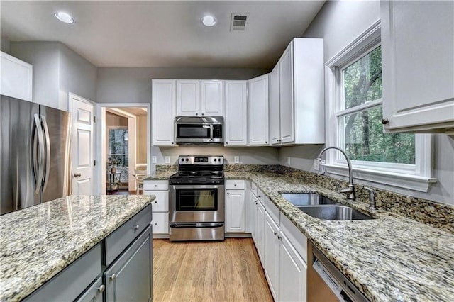 6520 Fairfield Trce, Suwanee, GA 30024 - kitchen featuring appliances with stainless steel finishes, white cabinets, light wood-style floors, light stone counters, and recessed lighting