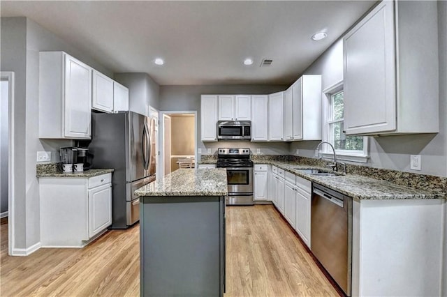 6520 Fairfield Trce, Suwanee, GA 30024 - kitchen featuring stainless steel appliances, a center island, light wood-style flooring, white cabinets, and light stone countertops
