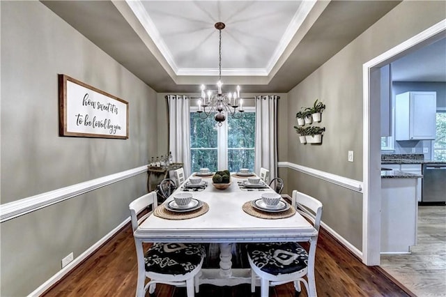 6520 Fairfield Trce, Suwanee, GA 30024 - dining space featuring a chandelier, a raised ceiling, wood finished floors, and crown molding