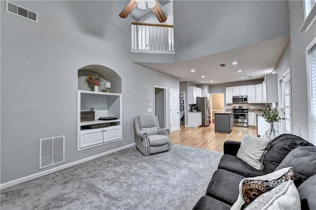 6520 Fairfield Trce, Suwanee, GA 30024 - living area featuring a high ceiling, ceiling fan, built in features, plenty of natural light, and light carpet