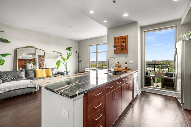 kitchen featuring dark stone counters, stainless steel fridge, sink, and dark hardwood / wood-style flooring