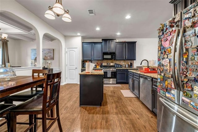 29 Madrid Ave, Newnan, GA 30263 - kitchen with stainless steel appliances, a sink, arched walkways, a chandelier, and wood finished floors