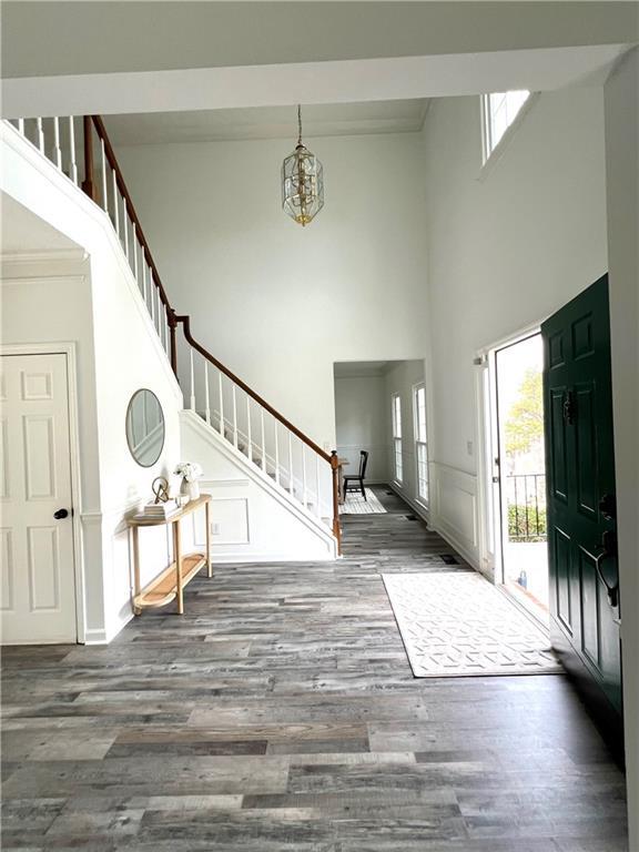 entrance foyer with an inviting chandelier, a towering ceiling, and dark wood-type flooring