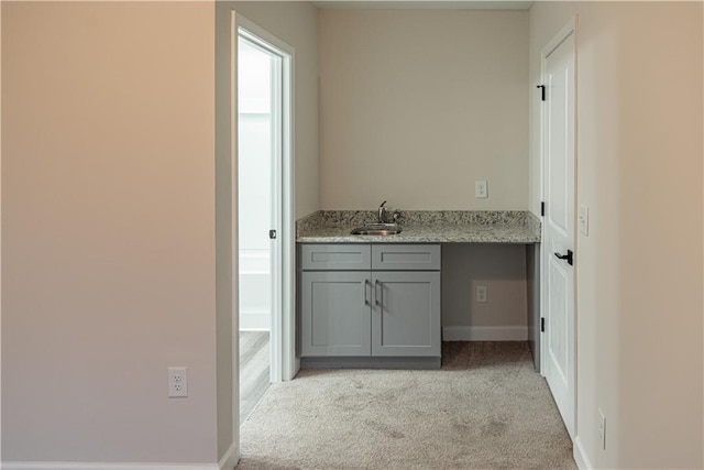 bar with gray cabinets, light stone countertops, sink, and light carpet