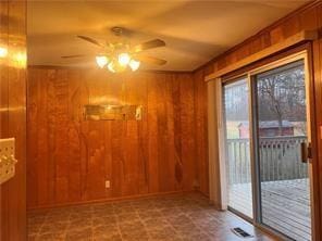 empty room featuring ceiling fan and wood walls