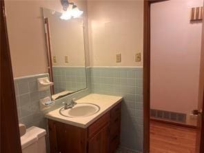 bathroom with hardwood / wood-style flooring, toilet, tile walls, and vanity