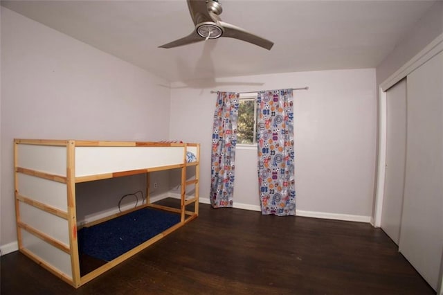 unfurnished bedroom with ceiling fan, a closet, and dark wood-type flooring