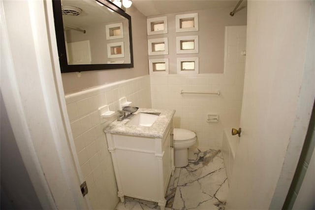 bathroom featuring vanity, toilet, and tile walls