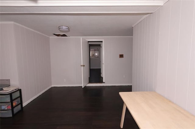 interior space with dark hardwood / wood-style flooring, wooden walls, and crown molding