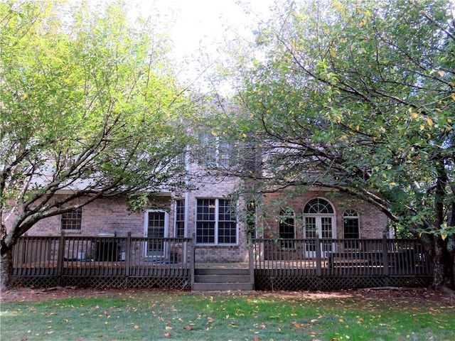 rear view of house with a wooden deck and a lawn