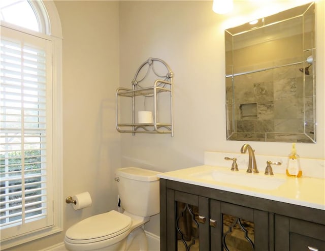 bathroom with vanity, a tile shower, and toilet